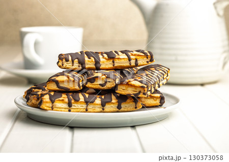 Sfogliatine glassate with chocolate. Italian crispy dessert on plate on white table. 130373058