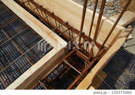 Steel reinforcement is placed in wooden molds and formwork on a construction site Steel reinforcement is placed in wooden molds and formwork on a construction site 130373060