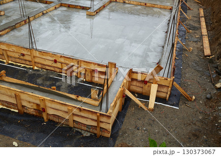 Construction of a concrete foundation with wooden forms at a building site on a cloudy day 130373067