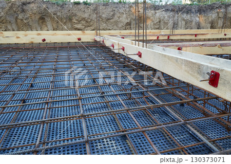 Steel reinforcement is placed in wooden molds and formwork on a construction site 130373071