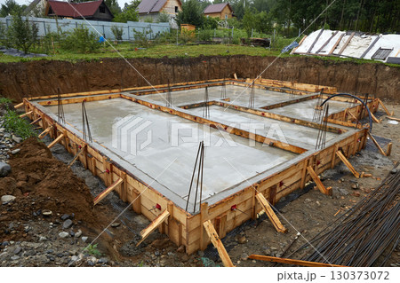Construction of a concrete foundation with wooden forms at a building site on a cloudy day 130373072