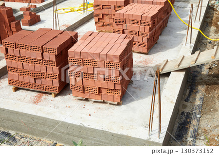 Bricks are neatly stacked on the construction site. Preparing materials for the construction of the building Bricks are neatly stacked on the construction site. Preparing materials for the construction of the building 130373152