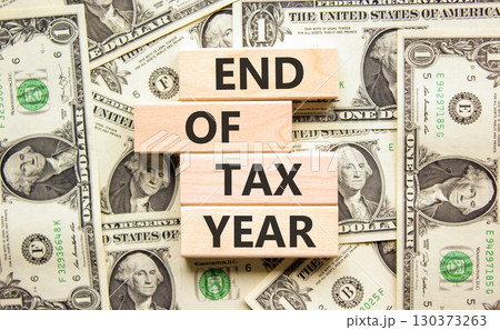 End of tax year symbol. Concept words phrase End of tax year on beautiful wooden blocks. Dollar bills. Beautiful dollar bills background. Business End of tax year concept. Copy space. End of tax year symbol. Concept words phrase End of tax year on beautiful wooden blocks. Dollar bills. Beautiful dollar bills background. Business End of tax year concept. Copy space. 130373263