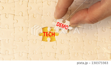 Tech demo symbol. Concept word Tech demo on beautiful white puzzles. Businessman's hand. Beautiful yellow paper background. Business tech demo concept. Copy space. Tech demo symbol. Concept word Tech demo on beautiful white puzzles. Businessman's hand. Beautiful yellow paper background. Business tech demo concept. Copy space. 130373363