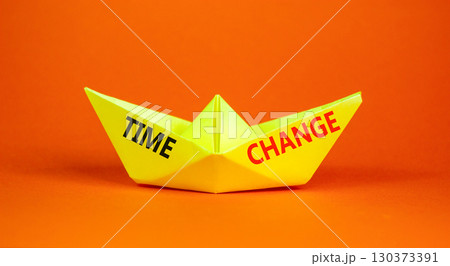Time change symbol. Concept word Time change on beautiful yellow paper boat. Beautiful orange paper background. Business time change concept. Copy space. Time change symbol. Concept word Time change on beautiful yellow paper boat. Beautiful orange paper background. Business time change concept. Copy space. 130373391
