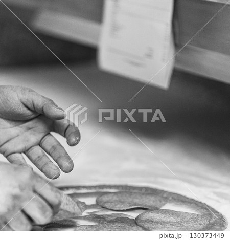 Hands preparing a pizza putting salami on pizza Hands preparing a pizza putting salami on pizza 130373449