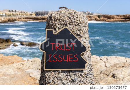 Trust issues symbol. Concept word Trust issues on beautiful black blackboard. Beautiful stone and blue sea sky background. Black blackboard. Business trust issues concept. Copy space. 130373477