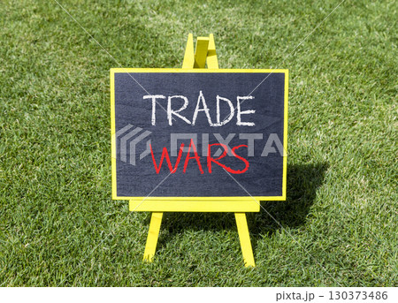 Trade wars symbol. Concept word Trade wars on beautiful black blackboard. Beautiful green grass lawn background. Black blackboard. Business trade wars concept. Copy space. Trade wars symbol. Concept word Trade wars on beautiful black blackboard. Beautiful green grass lawn background. Black blackboard. Business trade wars concept. Copy space. 130373486