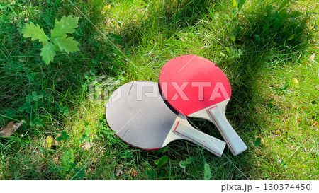 Table tennis rackets and balls on green grass, outdoor leisure 130374450