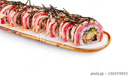 Sushi roll delicately arranged on a white plate with garnishes 130374953