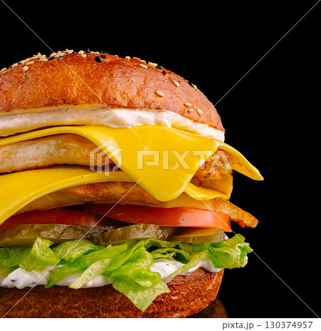 Juicy burger with fresh ingredients and melted cheese on a black background Juicy burger with fresh ingredients and melted cheese on a black background 130374957