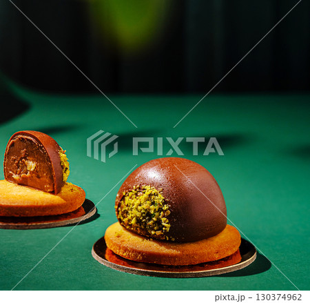 A unique chocolate dessert is displayed on a green textured surface A unique chocolate dessert is displayed on a green textured surface 130374962