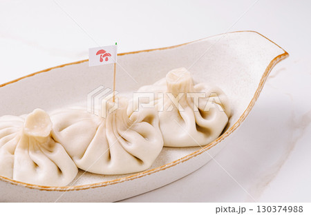 Three traditional Georgian khinkali dumplings served in a ceramic dish. Three traditional Georgian khinkali dumplings served in a ceramic dish. 130374988