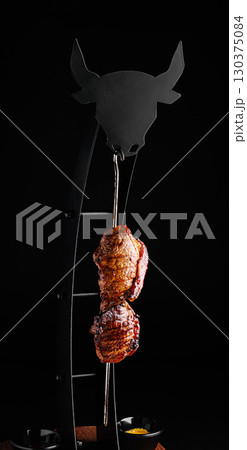 Juicy cut of meat hanging on a skewer in a modern dining setting Juicy cut of meat hanging on a skewer in a modern dining setting 130375084