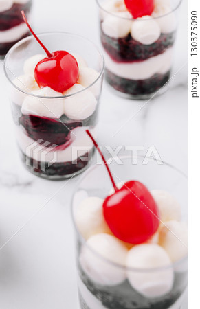 Layered dessert cups with cream and cherries create a sweet delight 130375090