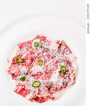 Fresh beef carpaccio with herbs and cheese served elegantly on a white plate 130375193