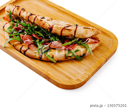 Delicious flatbread wrap filled with cured meats and fresh greens Delicious flatbread wrap filled with cured meats and fresh greens 130375201