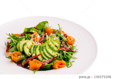 Fresh salad with avocado, smoked salmon, and pine nuts on a white plate 130375206