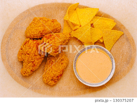 Crispy fried chicken served with tortilla chips and spicy sauce on a platter Crispy fried chicken served with tortilla chips and spicy sauce on a platter 130375207