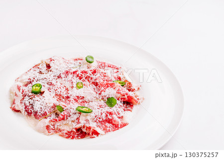 Gourmet beef carpaccio with fresh herbs and peppers served on a plate 130375257