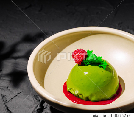 Delightful green dessert served with raspberry and mint garnish in elegant bowl Delightful green dessert served with raspberry and mint garnish in elegant bowl 130375258