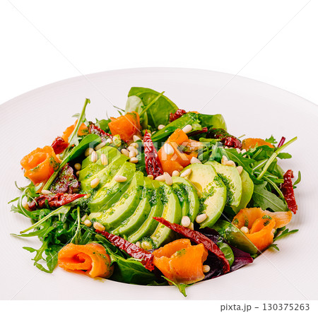 Fresh salad with avocado, smoked salmon, and herbs on a white plate 130375263