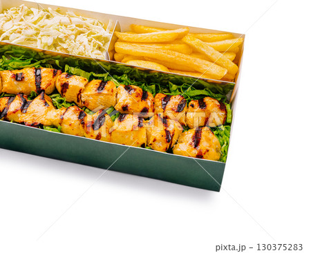 Grilled chicken skewers with coleslaw and golden fries served on a tray 130375283