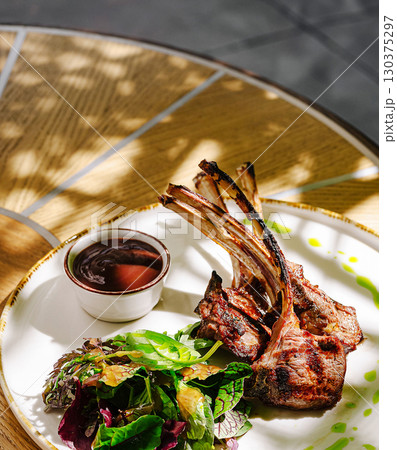 Delicious grilled lamb chops served with fresh salad and sauce 130375297