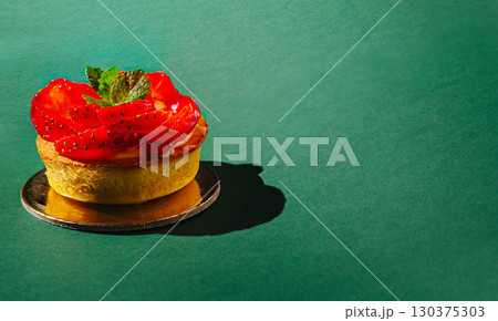 Fresh strawberry tartlet with mint on a green background Fresh strawberry tartlet with mint on a green background 130375303