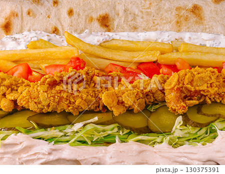 Fried chicken sandwich with fries, pickles, and fresh vegetables in a wrap Fried chicken sandwich with fries, pickles, and fresh vegetables in a wrap 130375391
