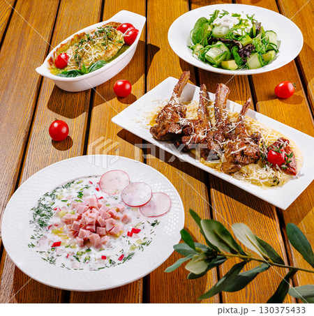 Delicious dinner spread featuring grilled lamb, salad, and baked dish Delicious dinner spread featuring grilled lamb, salad, and baked dish 130375433