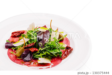 Fresh salad with arugula, dried tomatoes, and slices of carpaccio on a plate Fresh salad with arugula, dried tomatoes, and slices of carpaccio on a plate 130375444