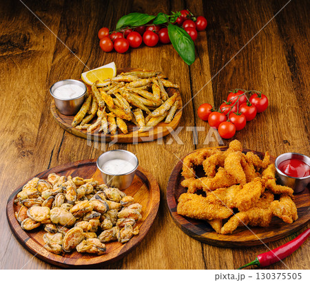 Fried seafood platter with garnishes and accompaniments on wooden table 130375505