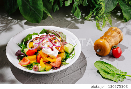 Fresh vegetable salad with colorful ingredients and herbs on a textured surface 130375508