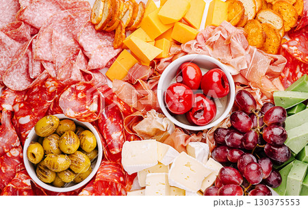Culinary display of assorted meats, cheeses, and fresh produce at a gathering 130375553
