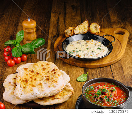 Delicious Indian meal with naan, curry, and fresh vegetables on wooden table 130375573