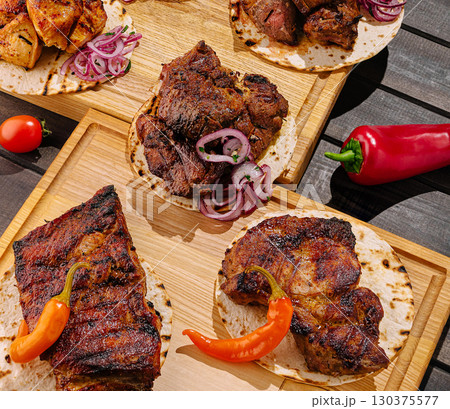Grilled meat served on tortillas with red onions and spices at a rustic setting 130375577