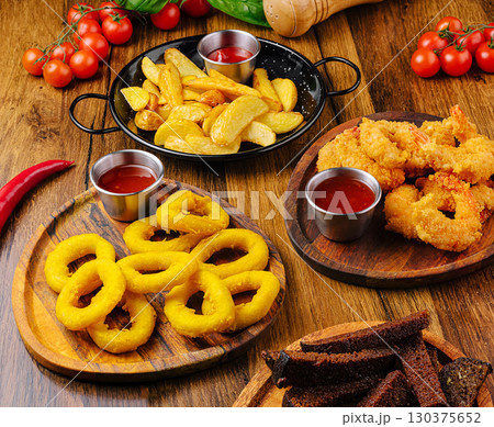 Delicious assortment of fried snacks served on wooden platters 130375652