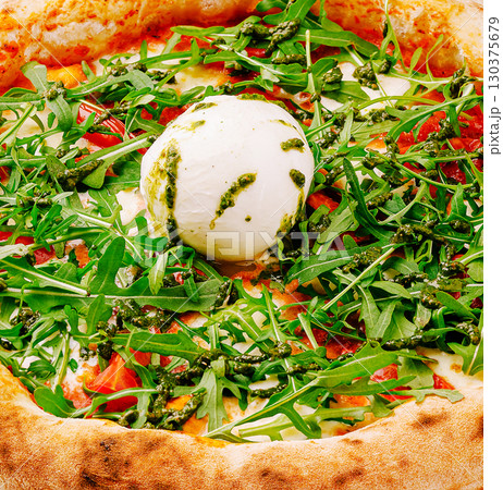 Freshly made pizza topped with arugula and creamy cheese at a rustic eatery 130375679