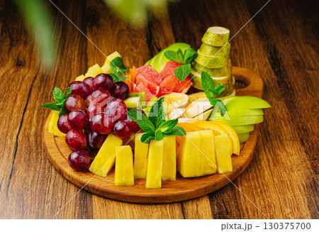 Fresh fruit platter served on wooden board with mint garnish 130375700