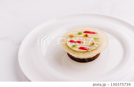Elegant dessert with layered textures and colorful decorations on a white plate 130375739
