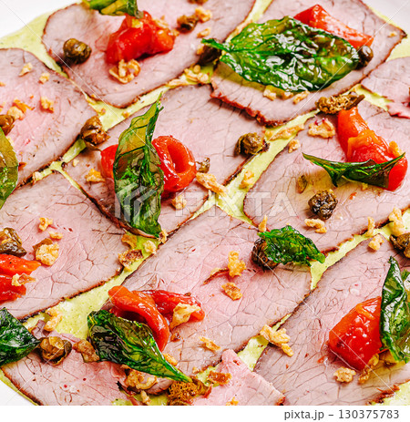 Tasty beef dish with fresh herbs and veggies on a white plate 130375783