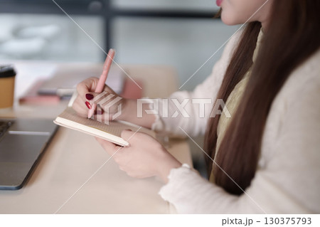 Asian adult freelancer writes notes notebook desk work study planning business remote productivity learning strategy content creation 130375793