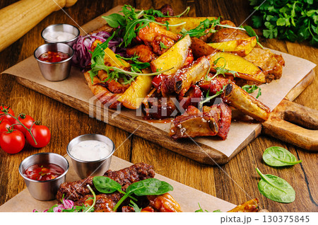 Delicious grilled meats and crispy potatoes served with fresh greens 130375845