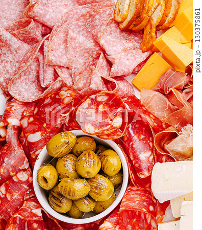 Charcuterie board featuring various meats, cheeses, and olives for a gathering Charcuterie board featuring various meats, cheeses, and olives for a gathering 130375861