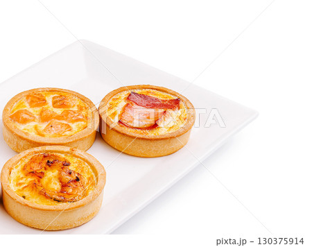 Mini savory tarts with assorted fillings showcased on a white plate Mini savory tarts with assorted fillings showcased on a white plate 130375914