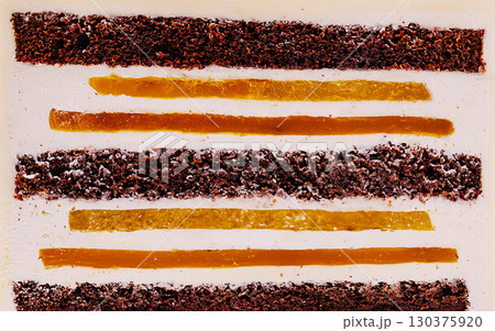 Colorful dessert layers with chocolate and fruit accents in artistic arrangement Colorful dessert layers with chocolate and fruit accents in artistic arrangement 130375920
