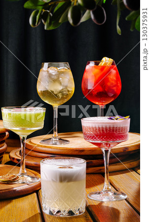 Colorful cocktails displayed on a wooden table at a lively bar setting 130375931