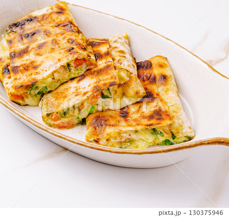 Delicious grilled wraps filled with vegetables and cheese served on a plate Delicious grilled wraps filled with vegetables and cheese served on a plate 130375946