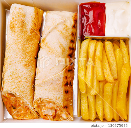 Delicious wraps with golden fries and dipping sauces in a takeout box Delicious wraps with golden fries and dipping sauces in a takeout box 130375953